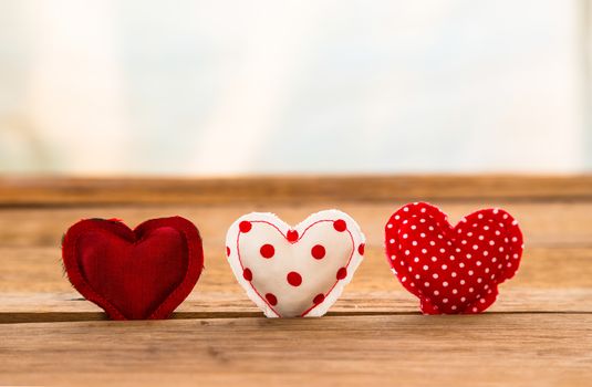 Group of Red hearts handmade craft from silk and cotton cloth put in hole of wood surface with white curtain on background, valentine's day and love symbol