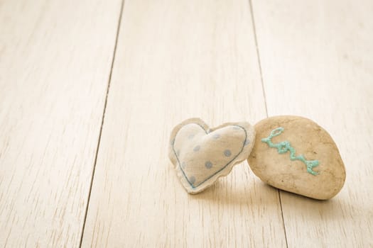Heart handmade craft from blue polka dot cotton cloth with glitter love word on pebble place on wood background,  anniversary and valentine's day symbol