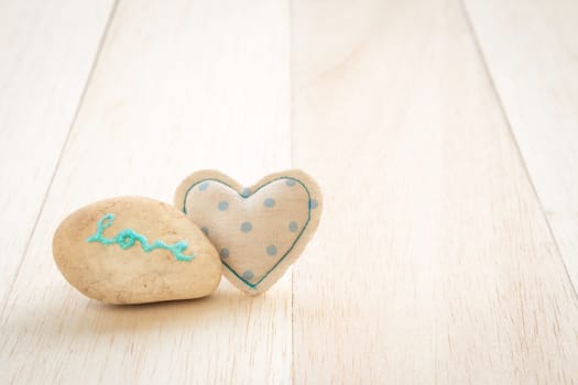 Cute heart handmade crafts from blue polka dot cotton cloth with glitter love word on stone place on wood background, love and valentine's day symbol
