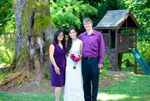 Beautiful biracial bride standing with her parents. Diversity.
