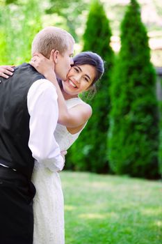 Caucasian groom lovingly kissing his biracial bride on cheek. Diverse couple