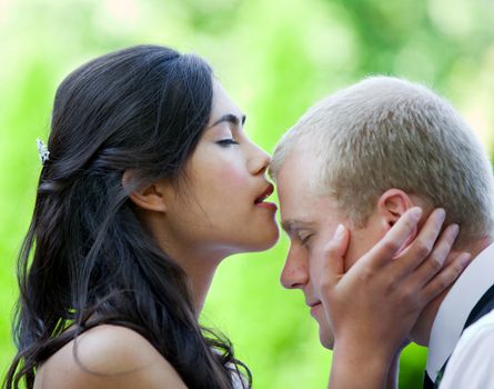 Biracial bride kissing Caucasian groom on forehead. Diverse couple