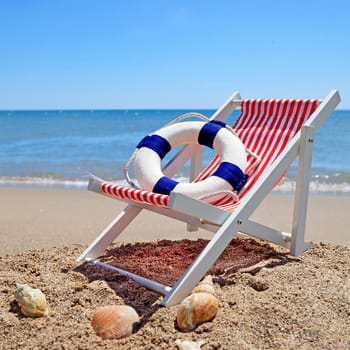 Beach chair near the ocean with shells on sunny day