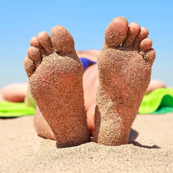 bottom of male feet covered with sand on the beach in sunshine 
