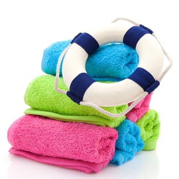 summer gear; colorful towels and life buoy over white background