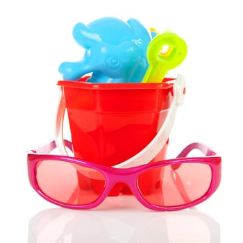 Colorful beach accessories; plastic toys and sunglasses over white background