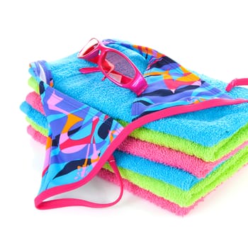 Pile of towels with bikini and pink sunglasses ovwe white background