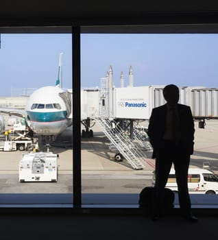 Osaka, Japan - Nov 7: Silhouette of a businessman waiting to board a Cathay Pacific passenger airplane in the Kansai International Airport in Osaka, Japan on Nov 7, 2014. Cathay Pacific is an international airline based in Hong Kong. It provides passenger and cargo services to 168 destinations in 42 countries worldwide.