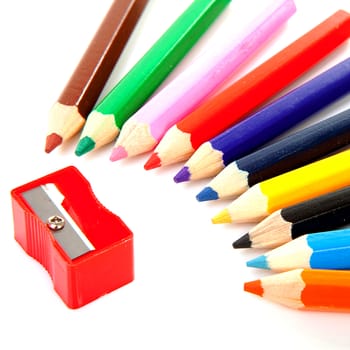 Colorful pencils and sharpener over white background