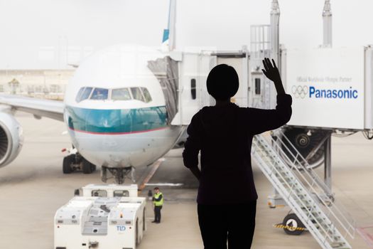 Osaka, Japan - Nov 7: Silhouette of a woman waving goodbye to a Cathay Pacific passenger airplane in the Kansai International Airport in Osaka, Japan on Nov 7, 2014. Cathay Pacific is an international airline based in Hong Kong. It provides passenger and cargo services to 168 destinations in 42 countries worldwide.