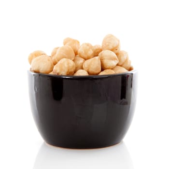 Bowl with hazelnuts over white background