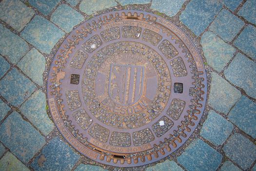 Iron hatch - manhole for sewer on cobblestone pavemant in Dresden, Germany