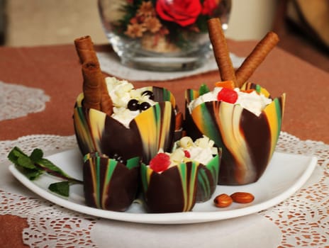 Chocolate tulip cups filled with curd dessert decorated with candied pineapple and chocolate chips