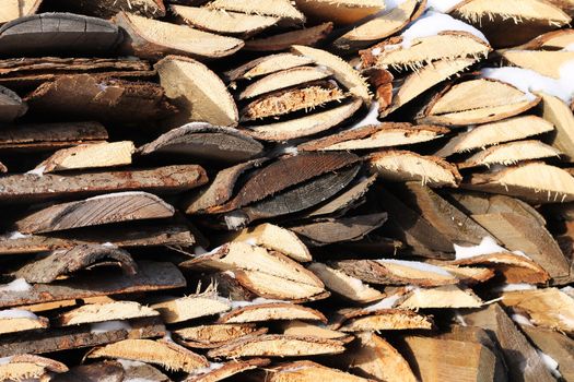 Background of stacked firewood in woodpile powdered white snow