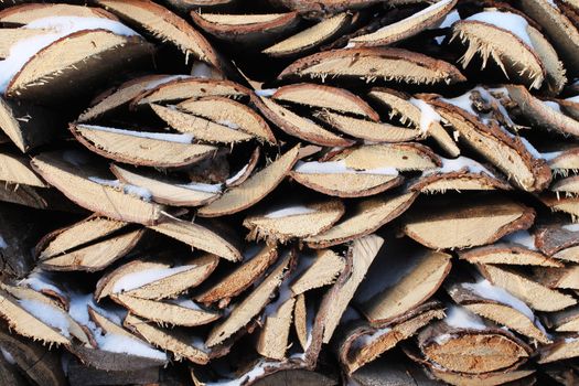 Background of stacked firewood in woodpile powdered white snow