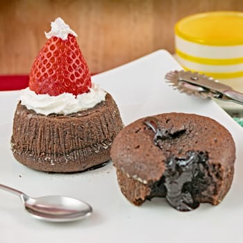 Plate with small chocolate cakes, strawberry and teaspoon