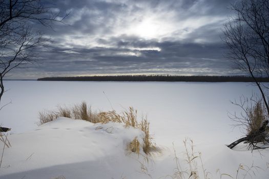 Frozen river Ob,the shore,the sun in the clouds.