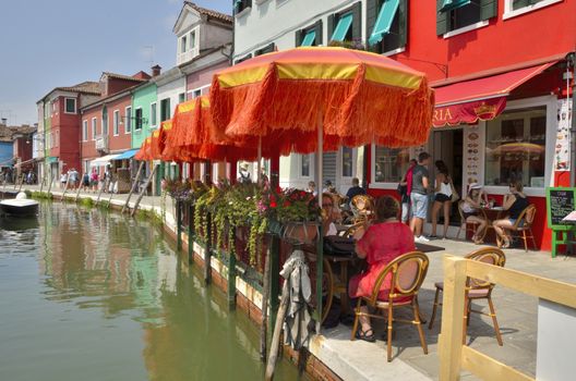 People eating in a colorfur outdoor restaurant in Burano, an island of Venice, Italy