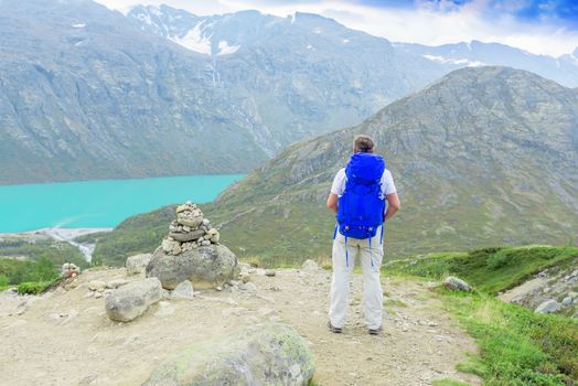 Back of a man with blue backpack in mountains looking away