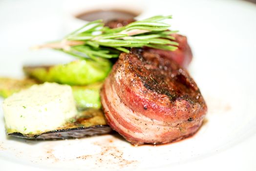 Grilled fillet mignon steak wrapped in bacon, with grilled vegetables, butter and rosemarie