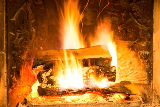 Burning fireplace with firewood and glowing ashes