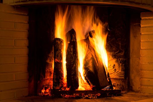 Burning fireplace with firewood and glowing ashes