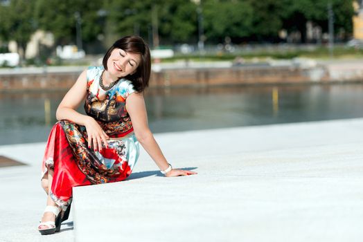 Brunette girl model in dress posing on exterior set