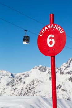 A red slope sign with a ski lift in the background