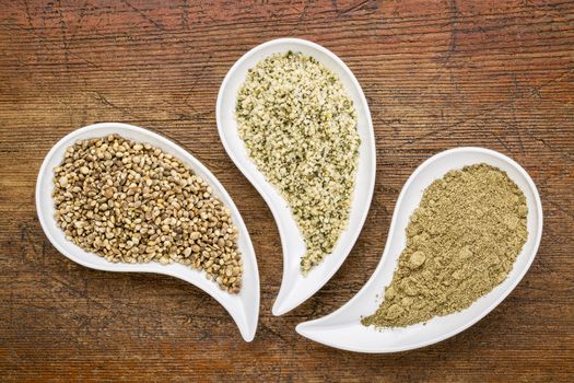 hemp seeds, hearts and protein powder in teardrop shaped bowls against grunge wood