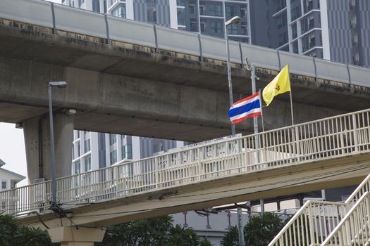 Thai flags waving in the wind, near a BTS station