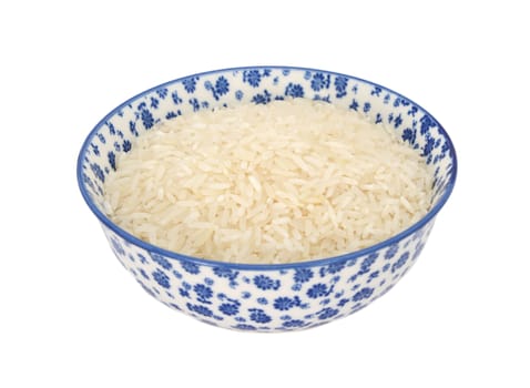 White long grain rice in a blue and white porcelain bowl with a floral design, isolated on a white background