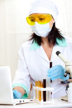 a female medical or scientific researcher or woman doctor looking at a test tube of black solution in a laboratory