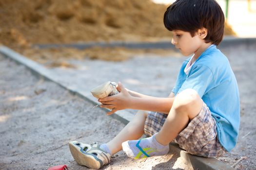 boy shakes the sand out of the shoe on the playground