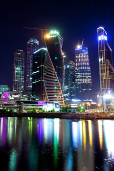 night Moscow City skyscrapers are reflected in the river