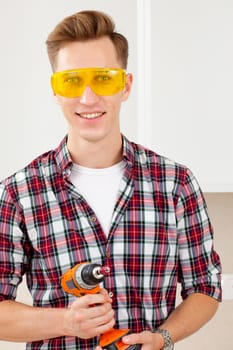 repairman in eyeglasses and with a drill in his hands