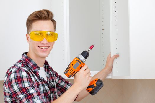 smiling worker assembles furniture with a drill in his hands