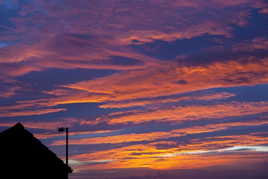 beautiful sunset with streetlight and rooftop in the foreground