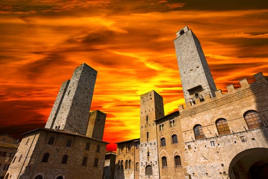 Buildings and towers in Piazza del Duomo at sunset, San Gimignano medieval town (UNESCO heritage), Siena, Tuscany, Italy