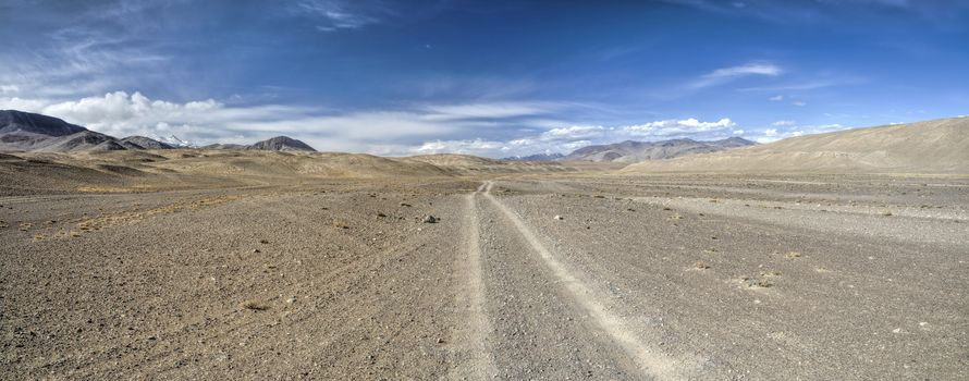 Scenic panorama of dirt road leading through arid landscape in Tajikistan