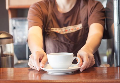 Barista offering white cup of coffee, stock photo