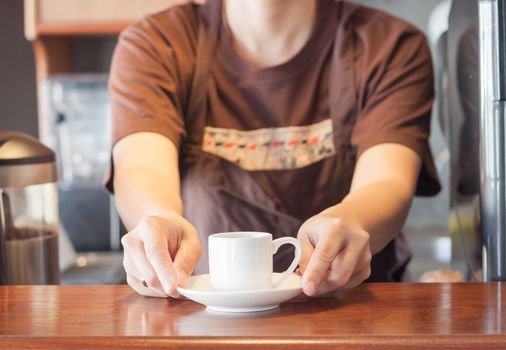 Barista offering mini white cup of coffee, stock photo