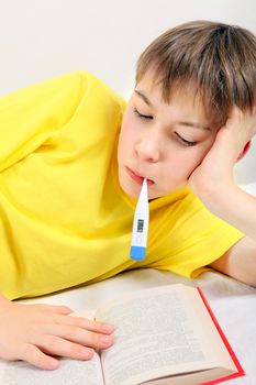 Sick Kid with a Book and Thermometer on the Bed