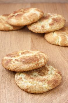 A stack of snicker doodles on a wooden surface.