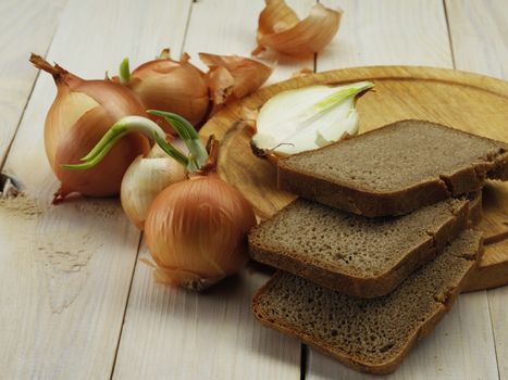 root of onion and bread on wooden board