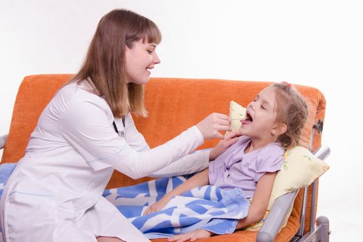 Doctor pediatrician examines a sick child at home