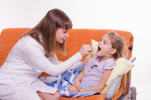 Doctor pediatrician examines a sick child at home