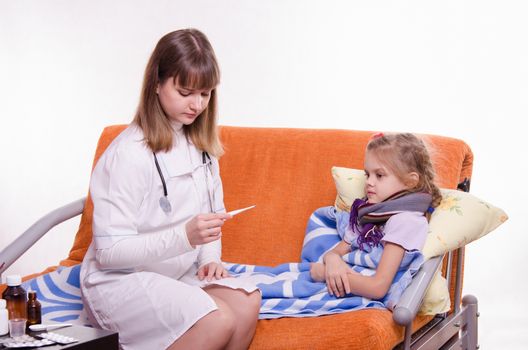 Doctor pediatrician examines a sick child at home