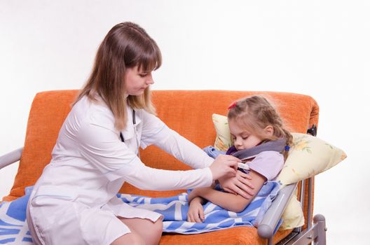 Doctor pediatrician examines a sick child at home