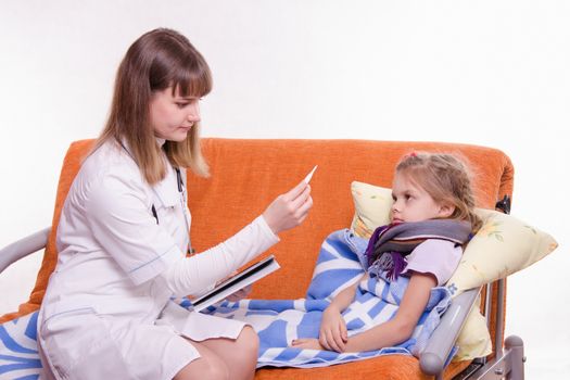 Doctor pediatrician examines a sick child at home