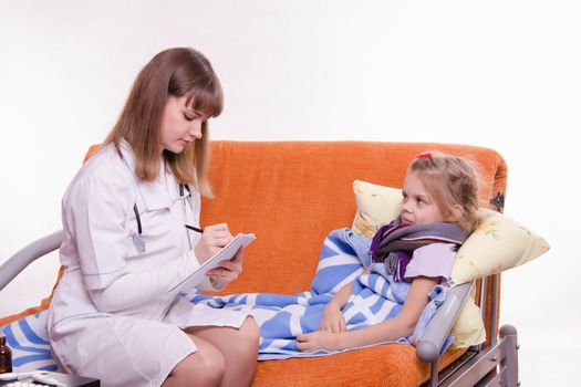 Doctor pediatrician examines a sick child at home